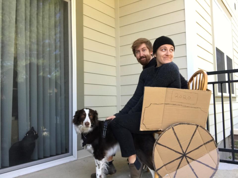 Man and woman in a cardboard cart with dog.