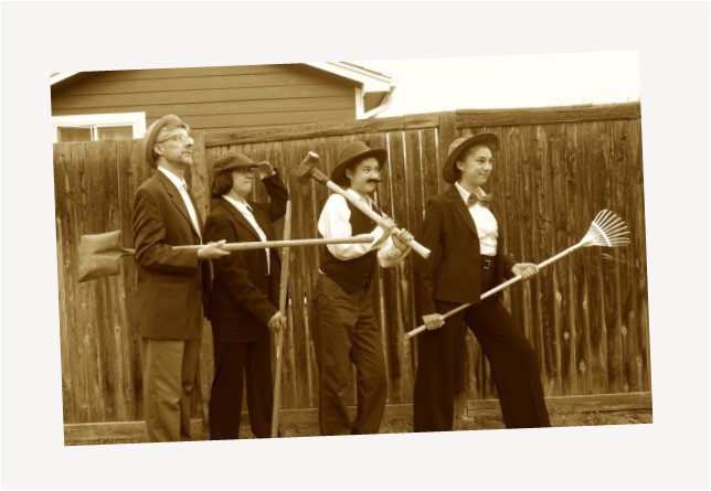 Three women and a man dressed in suits holding garden tools.