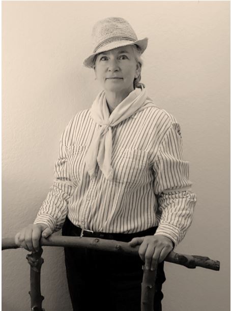 Woman in striped shirt, neck kerchief, and cowboy hat.