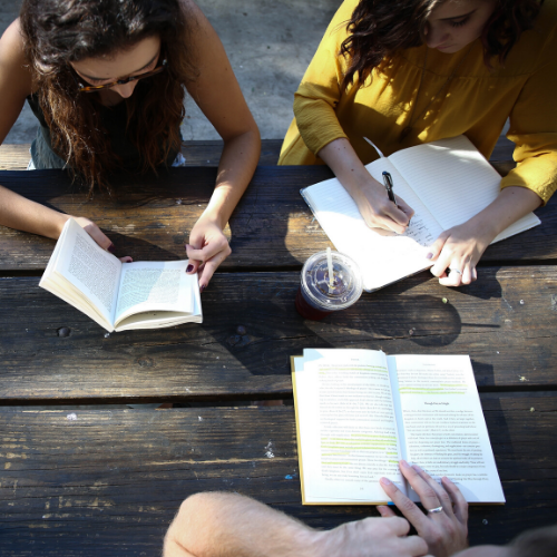 Three people reading and writing at a table