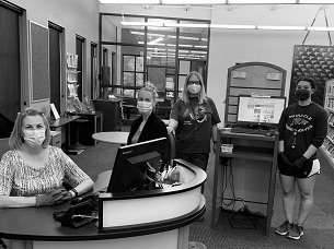 Four women posed by a reference desk with computers.