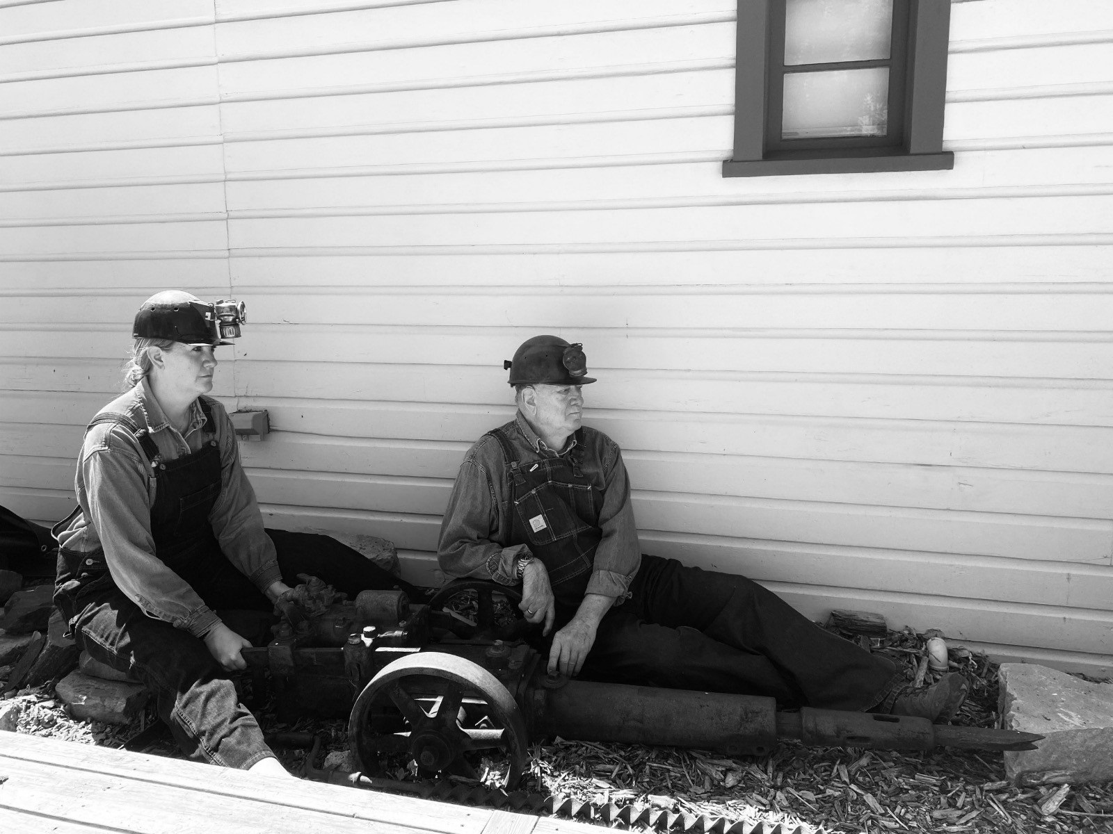 Woman and man sitting with a punching machine outside a building.