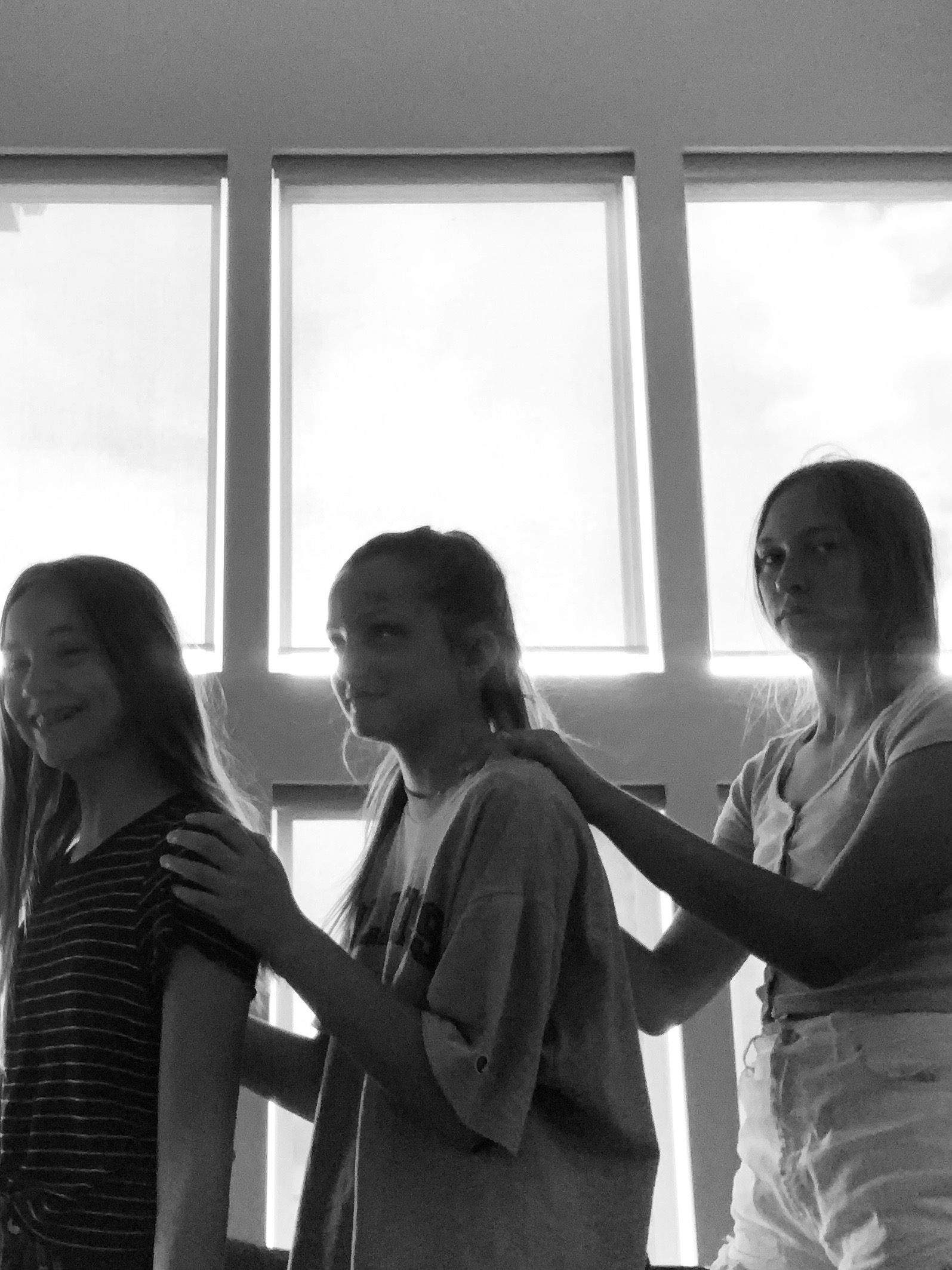 Three girls standing sideways in a row, looking at the camera.