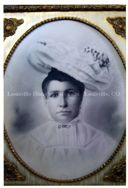 Old photo of woman in very large hat and high collared blouse.