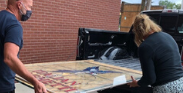 Man and woman loading stained glass window into tuck bed