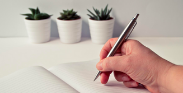 Photo of a person's hand writing in a journal