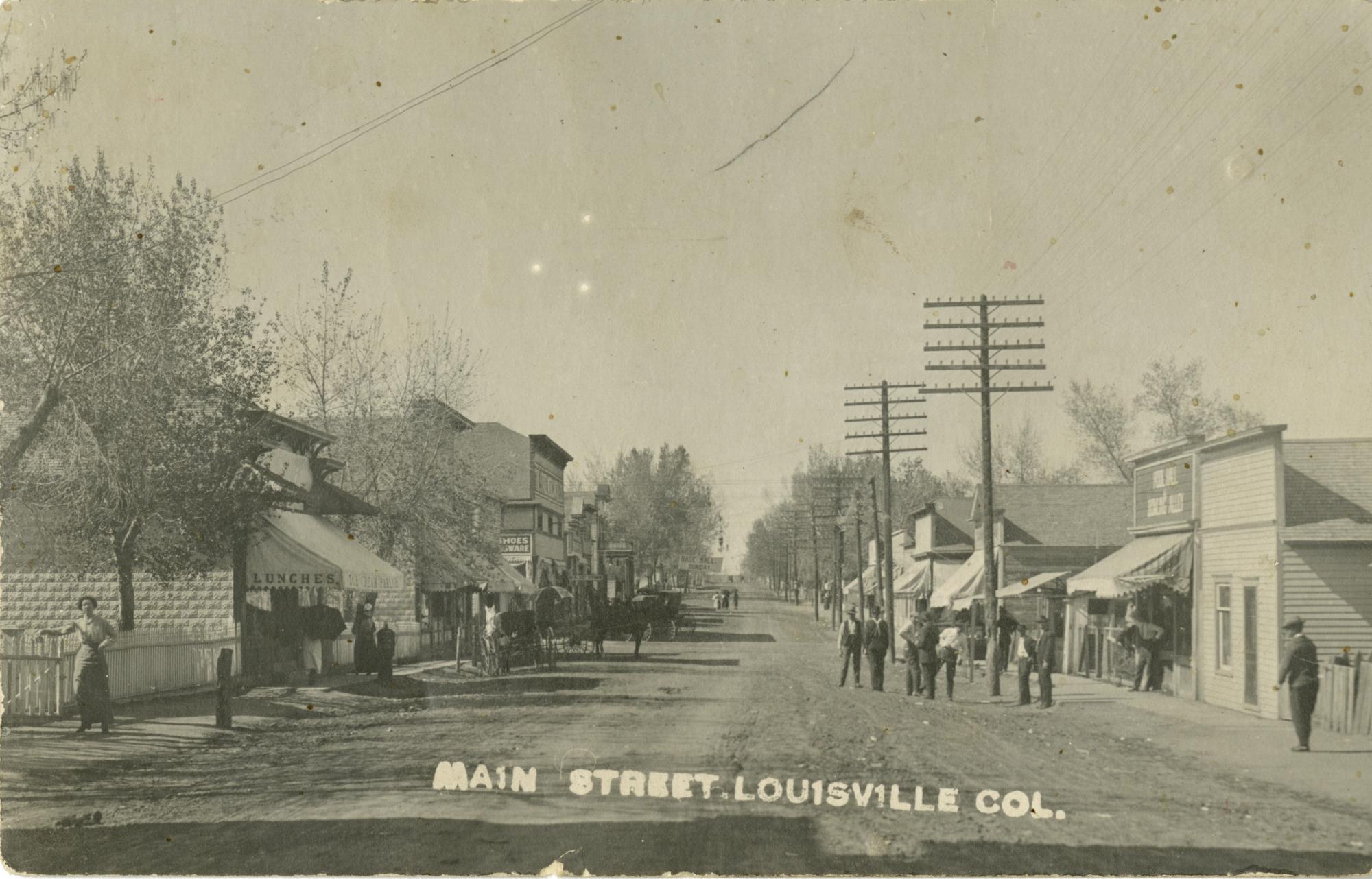 Main Street circa 1915 showing a few buildings and dirt road.