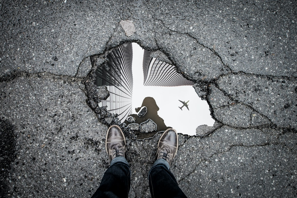 looking down at pothole with refection of airplane