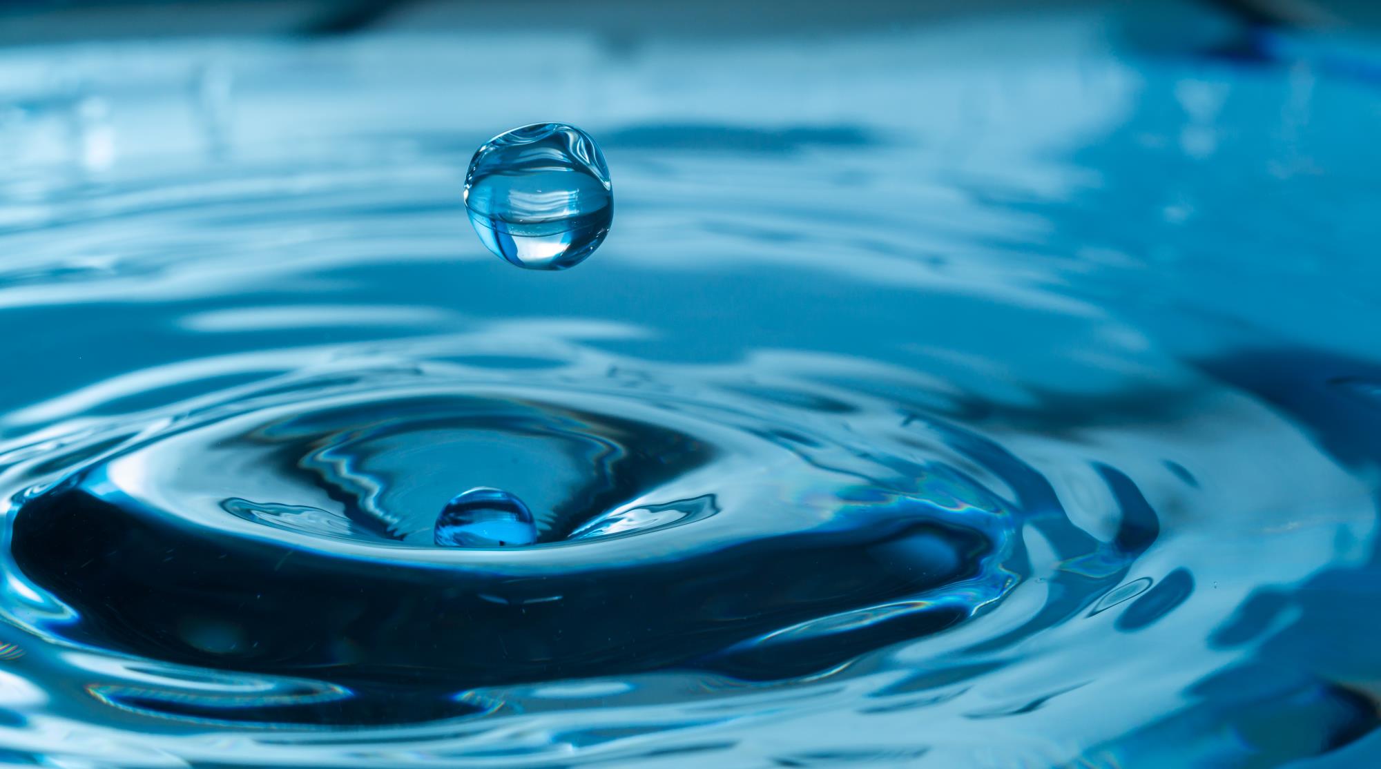 Round droplets of water falling into water