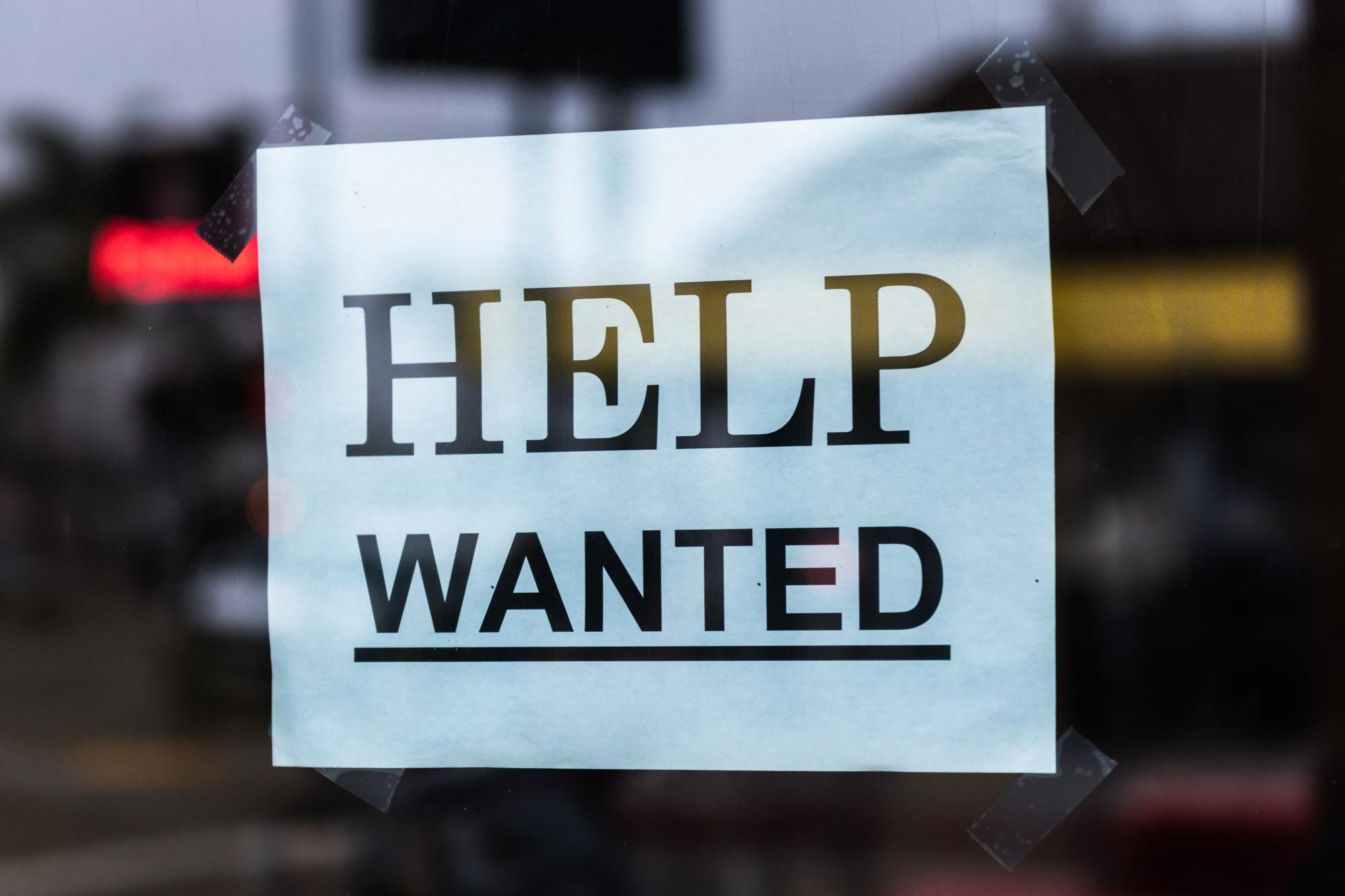 HELP WANTED SIGN TAPED TO WINDOW