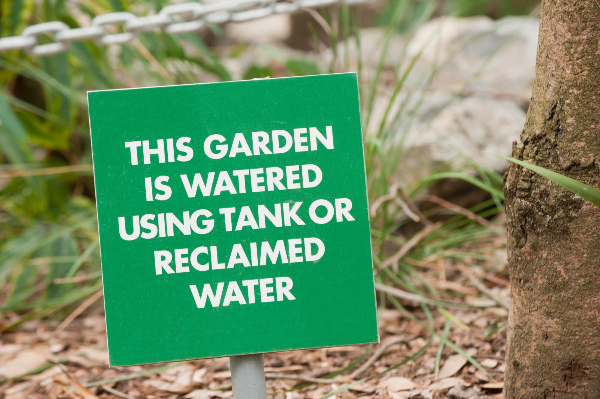 Sign in a garden that reads, "this garden  is watered using tank or reclaimed water"