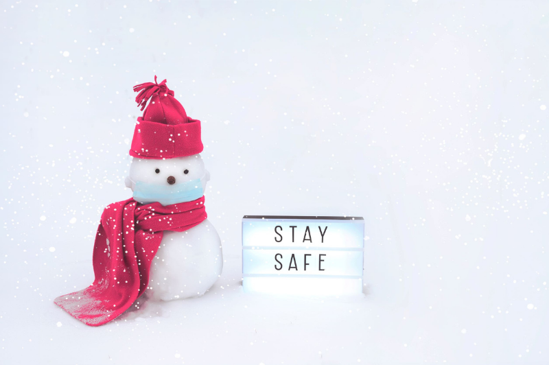 snowman in hat next to stay safe sign