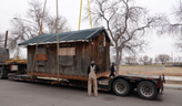 photo of wooden cabin being moved on a flatbed truck