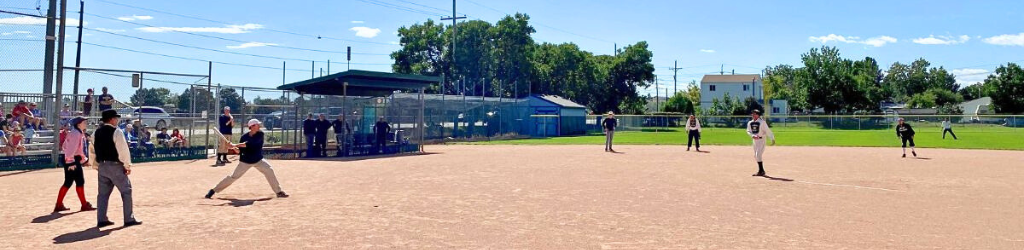 Men in old fashioned uniforms play baseball on a sunny day