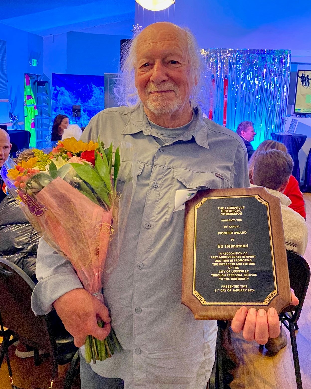 A man holding flowers and a plaque