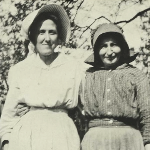 Two women in prairie style dresses and bonnets