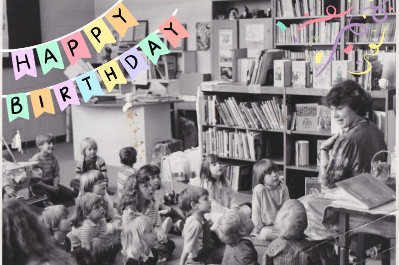 a black and white photo of a librarian reading to children, text reads Happy Birthday