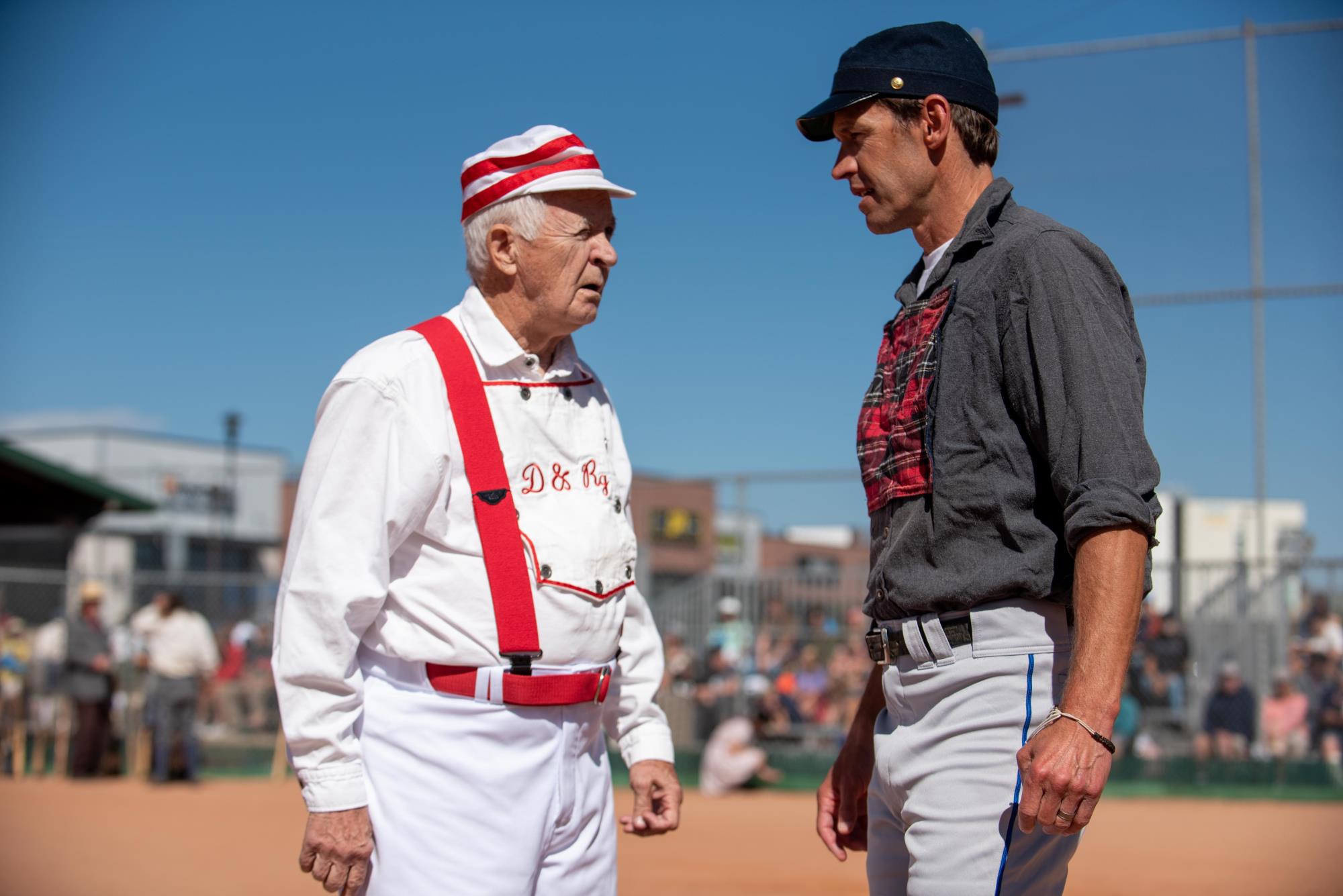 two men in vintage base ball uniforms talk face to face