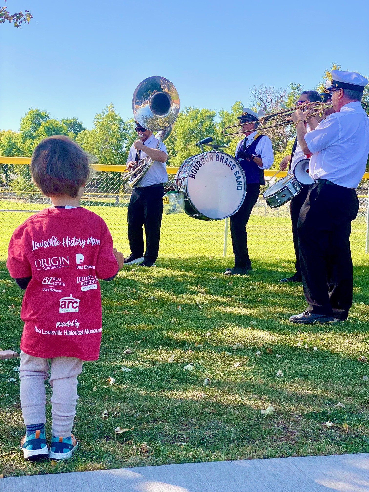 a small boy listens to music from the Bourbon Brass band