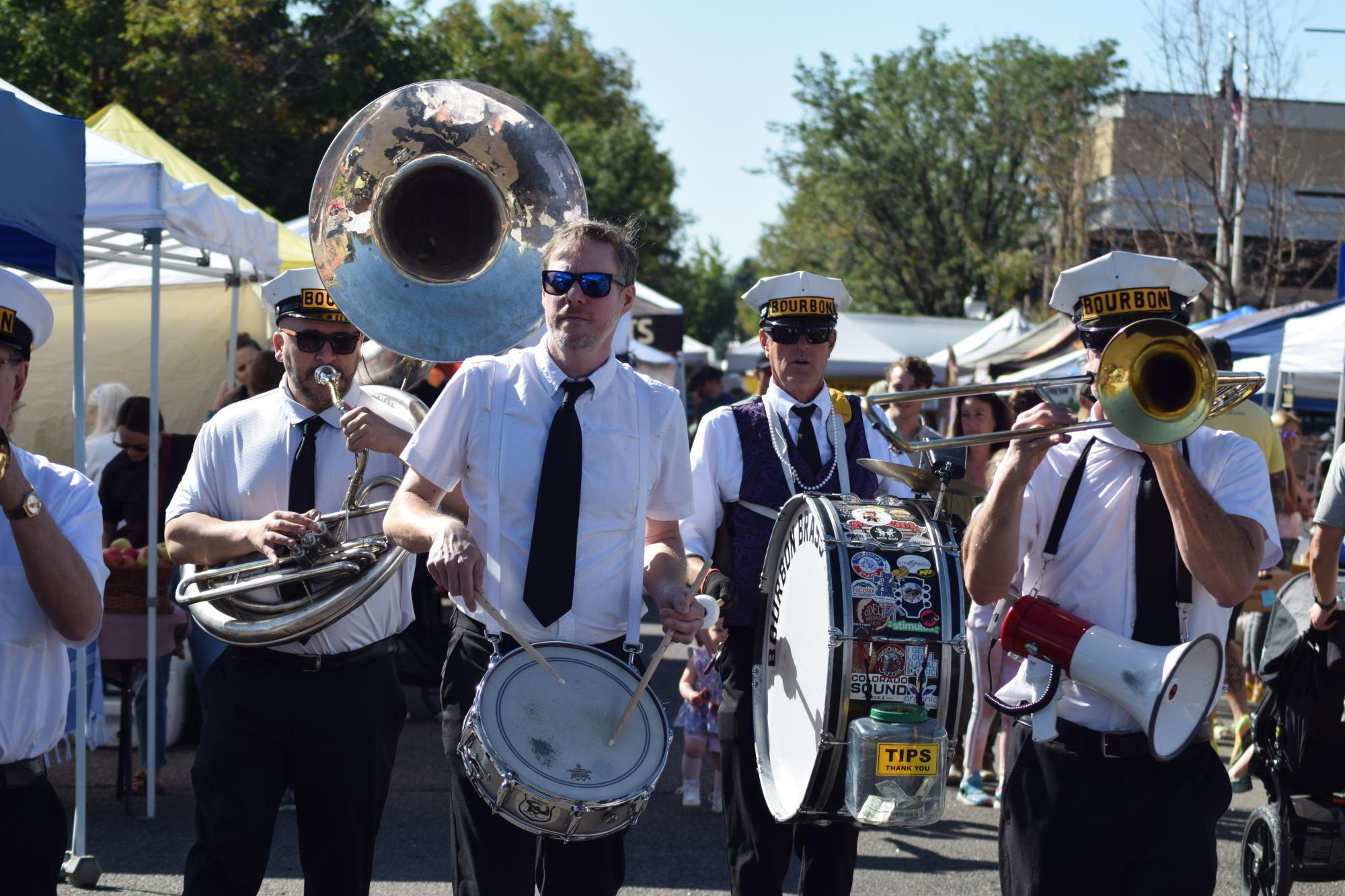 A brass band with tuba drum and trombone walk through a crowd